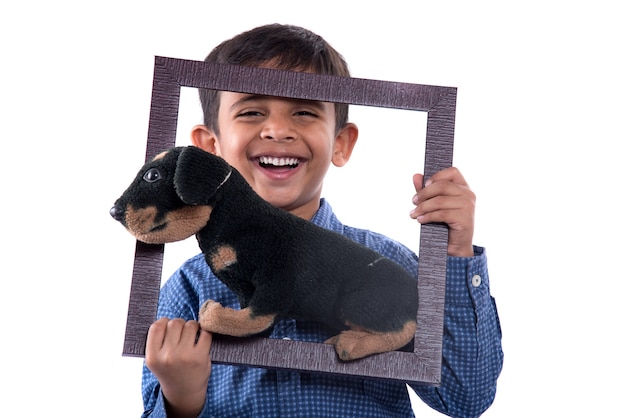 Porträt eines Jungen, der ausgestopftes Spielzeughaustier mit Rahmen hält
