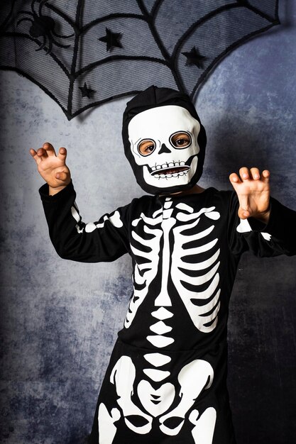 Foto porträt eines jungen, der ein halloween-kostüm trägt, während er gegen die wand gestimmt