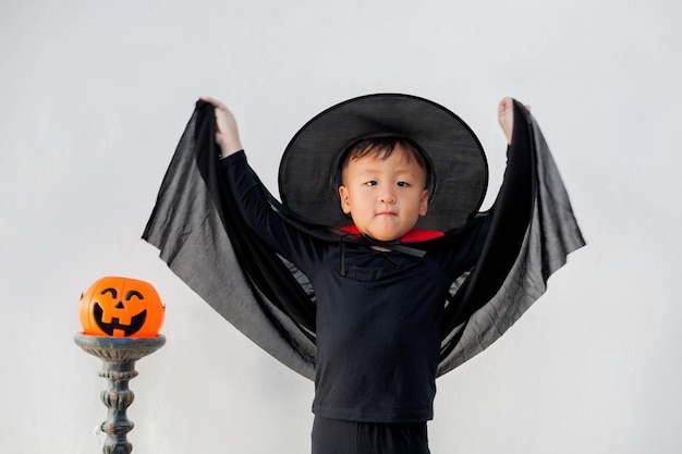 Porträt eines Jungen, der ein Hexenkostüm trägt, während er vor weißem Hintergrund steht