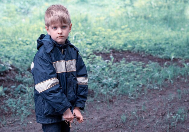 Foto porträt eines jungen, der einen regenmantel im wald trägt