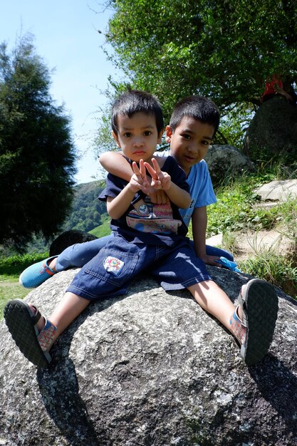 Foto porträt eines jungen, der mit seinem bruder auf einem felsen sitzt