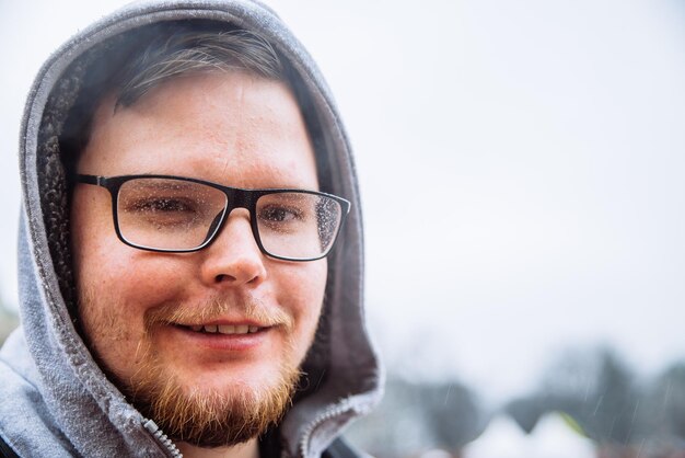 Foto porträt eines jungen erwachsenen mannes mit brille in tropfen und abdeckung mit kapuzenmann mit nassen haaren