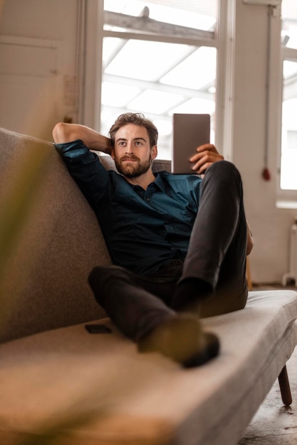 Porträt eines jungen Freiberuflers, der mit einem Tablet auf der Couch sitzt