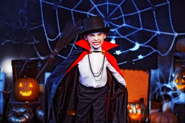 Porträt eines Jungen gekleidet in einem Kostüm eines Vampirs über Grunge-Hintergrund. Halloween Party.