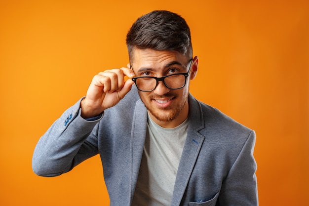 Porträt eines jungen Geschäftsmannes des intelligenten Mannes, der Brille gegen gelben Hintergrund trägt