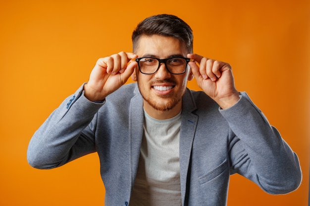 Porträt eines jungen Geschäftsmannes des intelligenten Mannes, der Brille gegen gelben Hintergrund trägt