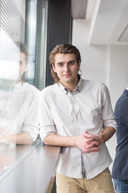 Foto porträt eines jungen geschäftsmannes im startup-büro am fenster