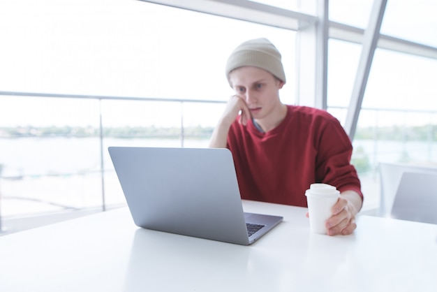 Porträt eines jungen Geschäftsmannes in der Freizeitkleidung, die an einem Laptop beim Mittagessen arbeitet