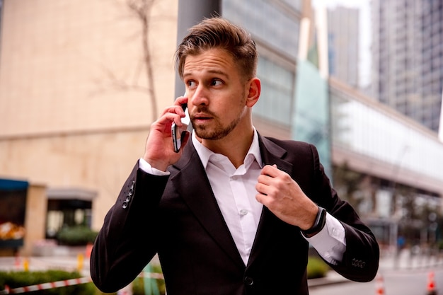 Porträt eines jungen Geschäftsmannes in einem Geschäftszentrum, das am Telefon spricht