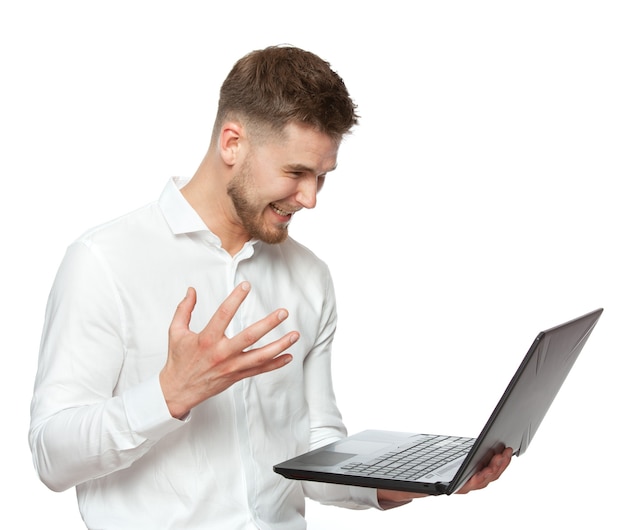 Porträt eines jungen Geschäftsmannes mit einem Laptop in den Händen drückt das Gefühl der Freude und der Gesten in einem weißen Hemd aus, das auf einem weißen Hintergrund lokalisiert wird.