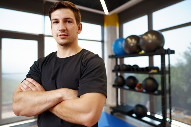 Porträt eines jungen gutaussehenden Fitnesstrainers in einem Fitnessstudio