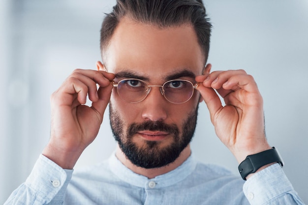 Porträt eines jungen gutaussehenden Mannes in formeller Kleidung drinnen im Büro tagsüber