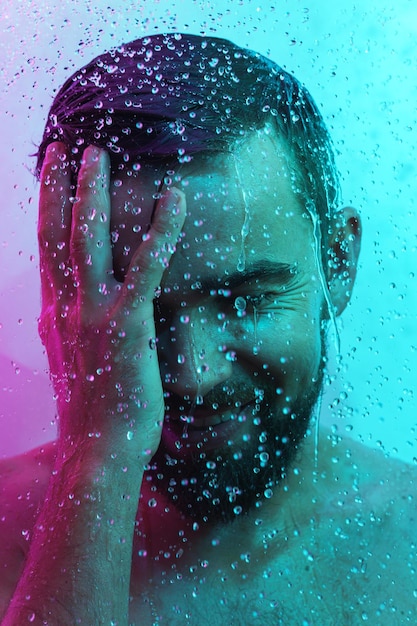 Porträt eines jungen gutaussehenden Mannes unter Wasserfluss im Neonlicht