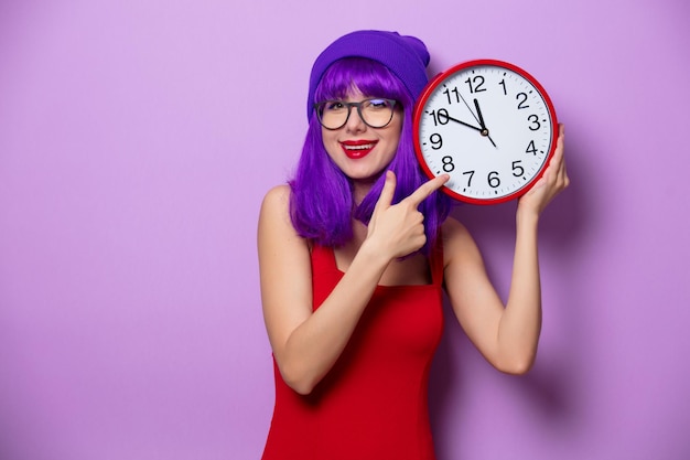 Porträt eines jungen Hipster-Mädchens mit lila Haaren und großer Uhr auf lila Hintergrund