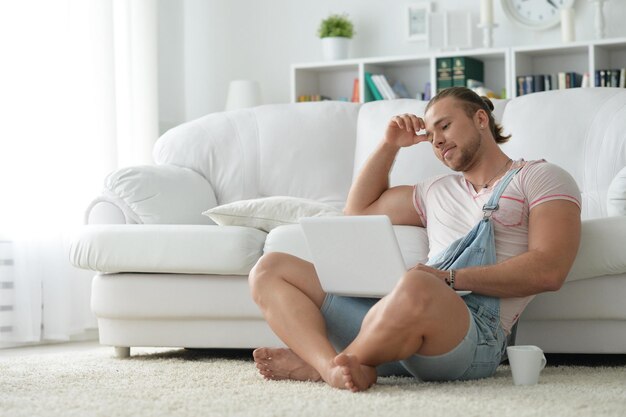 Porträt eines jungen Hipster-Mannes, der zu Hause Zeit mit Laptop verbringt