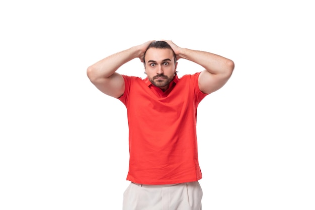 Porträt eines jungen hübschen Mannes mit schwarzen Haaren und Bart, gekleidet in einem roten Firmenfarben-T-Shirt