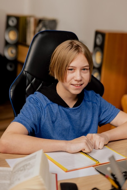 Porträt eines Jungen im Grundschulalter, der in einem Raum auf einem bequemen Stuhl an einem Schreibtisch sitzt