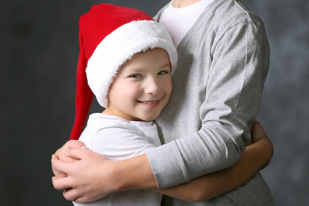 Porträt eines Jungen in Weihnachtsmütze auf grauem Hintergrund, Nahaufnahme