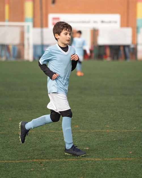 Porträt eines jungen Jungen, der während eines Spiels bei kaltem Wetter auf dem Fußballplatz im Stadion spielt