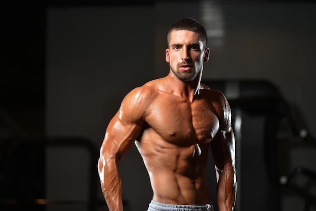 Porträt eines jungen körperlich fitten Mannes, der seinen gut trainierten Körper zeigt muskulöser athletischer Bodybuilder Fitness Model posiert nach Übungen