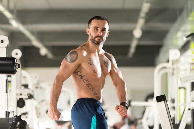 Porträt eines jungen körperlich fitten Tätowierers, der seinen gut trainierten Körper zeigt muskulöser athletischer Bodybuilder Fitness Model posiert nach Übungen