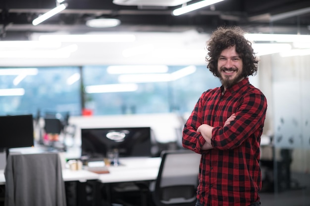 Porträt eines jungen, lächelnden, erfolgreichen männlichen Softwareentwicklers, der im modernen Startup-Büro steht