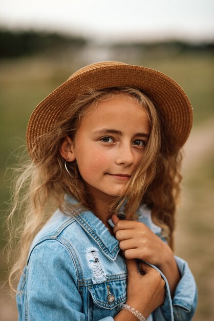 Porträt eines jungen Mädchens, das im Sommer ruht und in einem Hut auf dem Feld geht