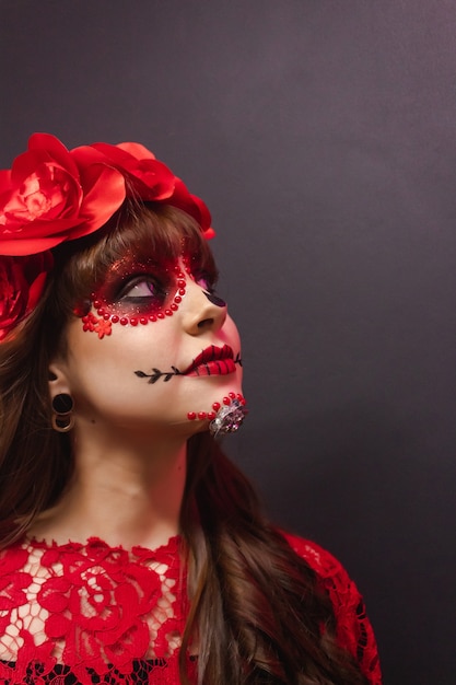 Porträt eines jungen Mädchens, das mit Dia de los Muertos Make-up oben schaut.