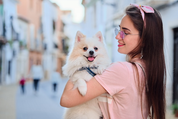 Porträt eines jungen Mädchens, das mit einem weißen flaumigen Spitz geht.