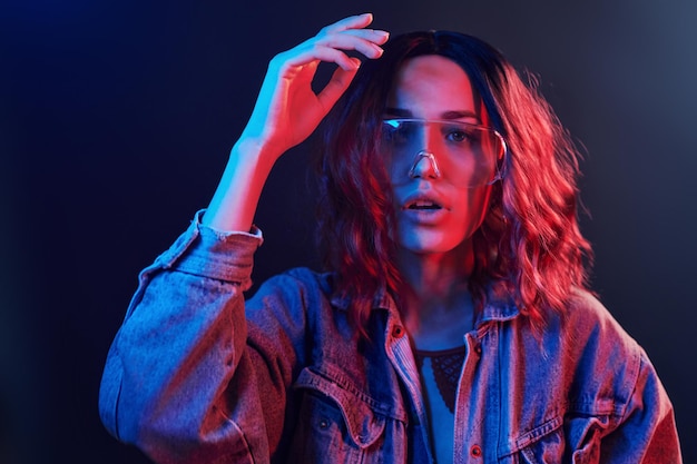 Porträt eines jungen Mädchens mit Brille in rotem und blauem Neon im Studio