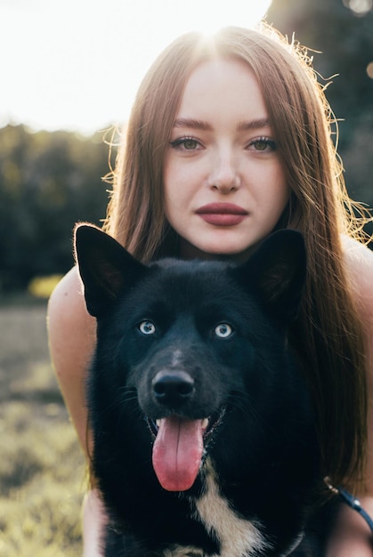 Porträt eines jungen Mädchens mit europäischem Aussehen in einer Umarmung mit einem schwarzen Hund Laika