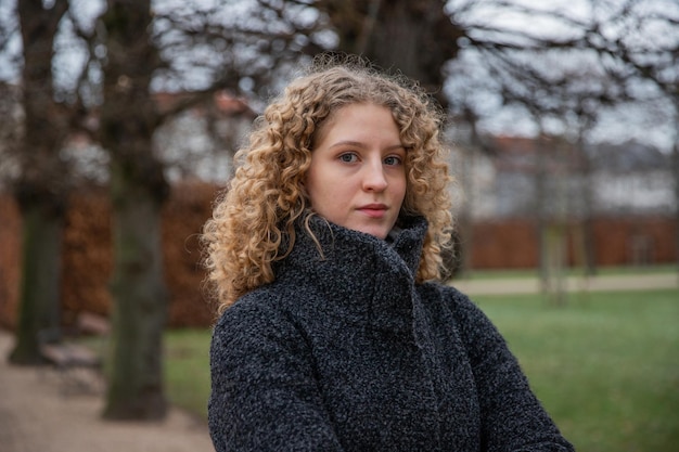 Porträt eines jungen Mädchens mit lockigem Haar in einem öffentlichen Park an einem Wintertag