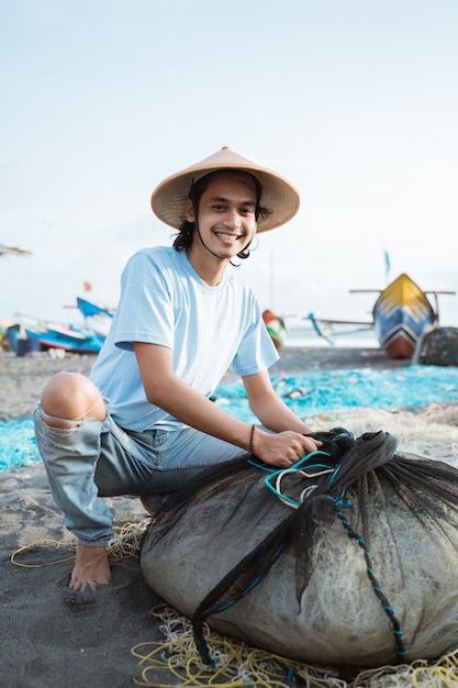 Porträt eines jungen männlichen Fischers, der ein Fischernetz vorbereitet