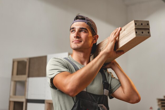 Foto porträt eines jungen männlichen tischlers, der in der holzwerkstatt steht