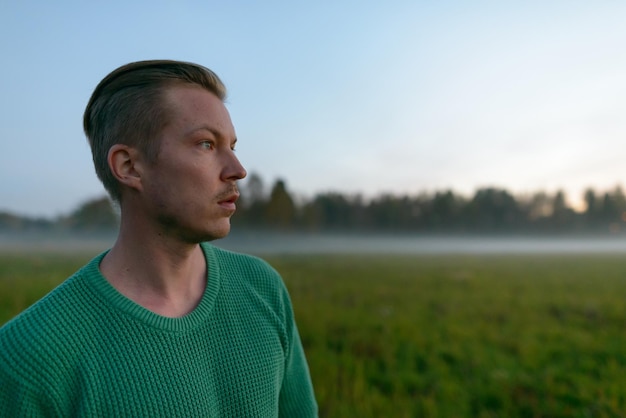 Foto porträt eines jungen mannes, der auf dem feld gegen den himmel wegblickt