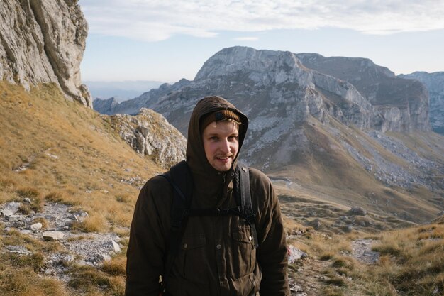 Porträt eines jungen Mannes, der auf einer Landschaft gegen Berge steht