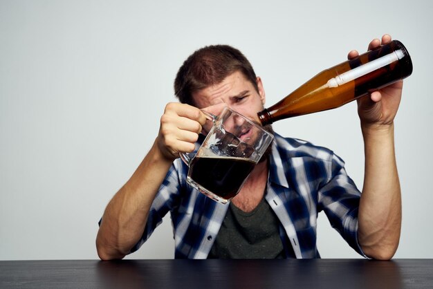 Foto porträt eines jungen mannes, der ein glas auf dem tisch trinkt