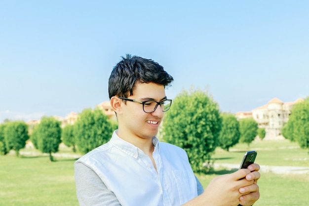 Porträt eines jungen Mannes, der ein Smartphone gegen den Himmel benutzt