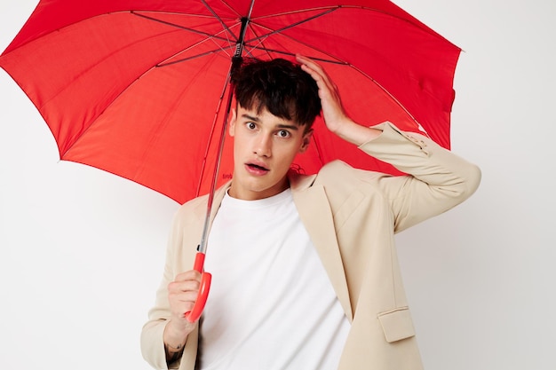 Porträt eines jungen Mannes, der einen Regenschirm in den Händen hält, um den hellen Hintergrund der Mode unverändert zu posieren