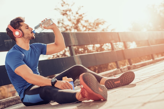 Porträt eines jungen Mannes, der etwas Wasser aus einer Flasche trinkt