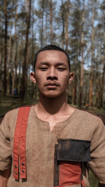 Foto porträt eines jungen mannes, der gegen bäume steht