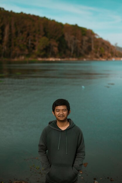 Foto porträt eines jungen mannes, der gegen den see steht