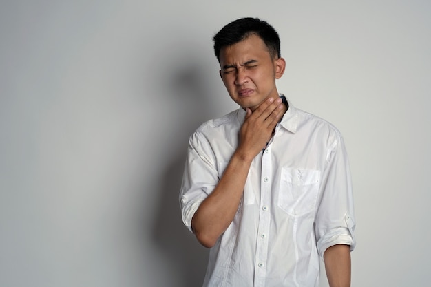Porträt eines jungen Mannes, der Halsschmerzen hat und seinen Hals mit der Hand berührt