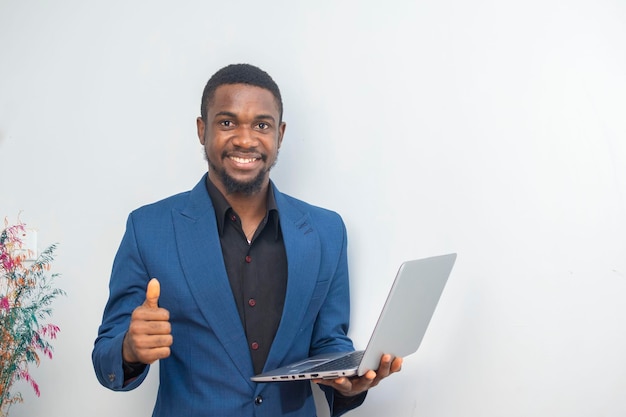 Porträt eines jungen Mannes, der im Büro steht und seinen Laptop bedient