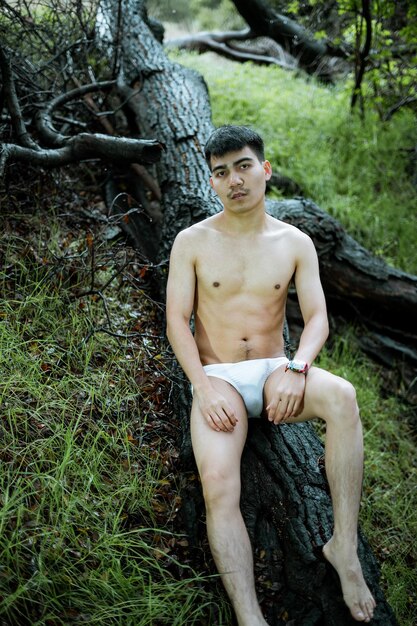 Foto porträt eines jungen mannes, der im wald sitzt