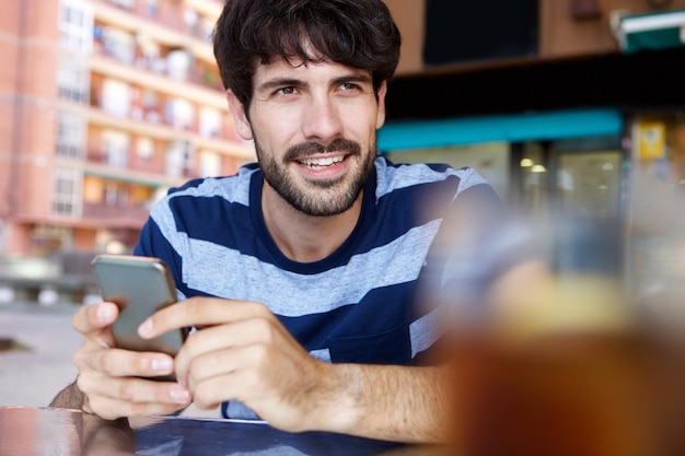 Porträt eines jungen Mannes, der mit seinem Mobiltelefon im Café sitzt