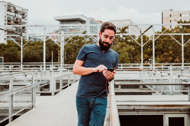 Foto porträt eines jungen mannes, der musik hört, während er auf einer fußgängerbrücke steht