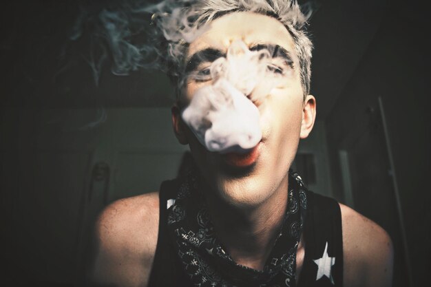 Foto porträt eines jungen mannes, der rauch bläst