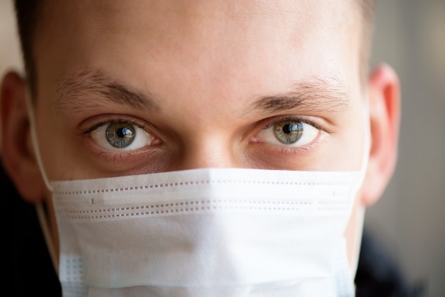 Porträt eines jungen Mannes, der Schutzgesichtsmaske gegen Coronavirus im Flughafen trägt