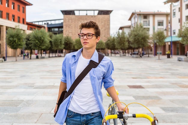 Porträt eines jungen Mannes, der sein Fahrrad schiebt
